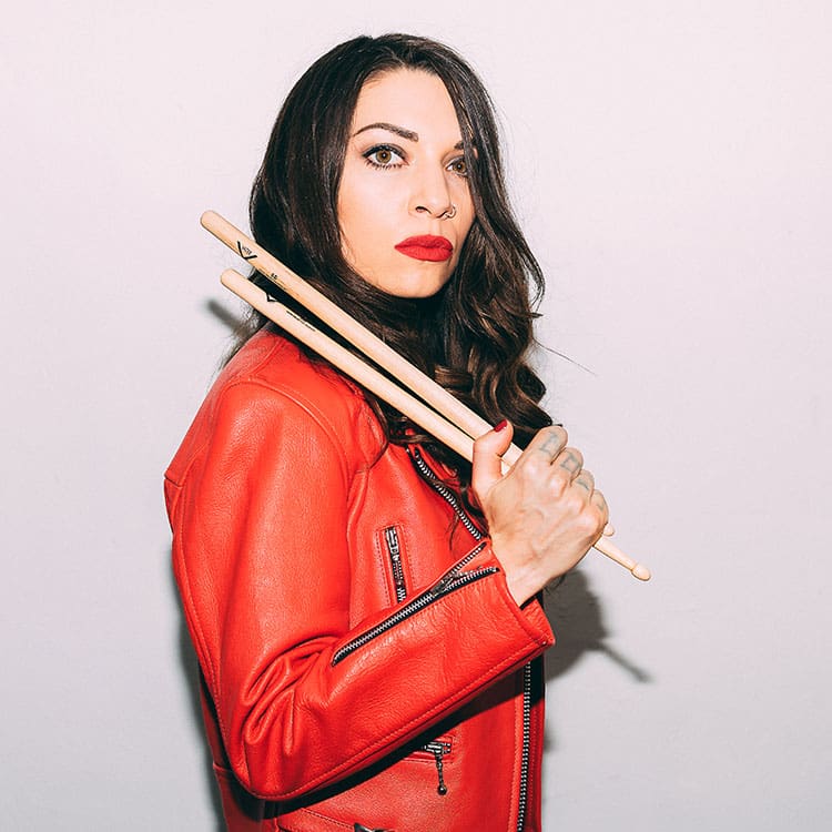 photo of Jessica Goodwin holding sticks above her shoulders wearing a red leather-look jacket